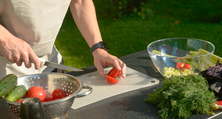 man preparing salad of onions cucumbers and tomatoes in the backyard.close-up of hands with vegetables.hands preparing salad of vegetables onions tomatoes cucumbers