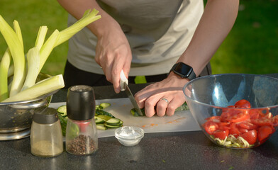 man preparing salad of onions cucumbers and tomatoes in the backyard.close-up of hands with vegetables.hands preparing salad of vegetables onions tomatoes cucumbers