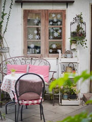 Terrace Table and chair. A vintage scene of outdoor table and chair by the wooden window, with red gingham pillows on the chair. Vintage Patio Furniture.