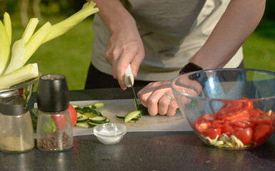 man preparing salad of onions cucumbers and tomatoes in the backyard.close-up of hands with vegetables.hands preparing salad of vegetables onions tomatoes cucumbers