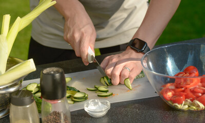 man preparing salad of onions cucumbers and tomatoes in the backyard.close-up of hands with vegetables.hands preparing salad of vegetables onions tomatoes cucumbers