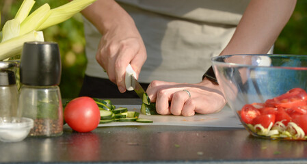 man preparing salad of onions cucumbers and tomatoes in the backyard.close-up of hands with vegetables.hands preparing salad of vegetables onions tomatoes cucumbers