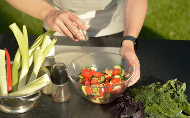 man preparing salad of onions cucumbers and tomatoes in the backyard.close-up of hands with vegetables.hands preparing salad of vegetables onions tomatoes cucumbers