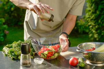 man preparing salad of onions cucumbers and tomatoes in the backyard.close-up of hands with vegetables.hands preparing salad of vegetables onions tomatoes cucumbers