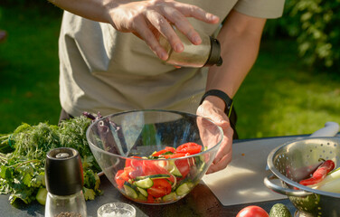 man preparing salad of onions cucumbers and tomatoes in the backyard.close-up of hands with vegetables.hands preparing salad of vegetables onions tomatoes cucumbers