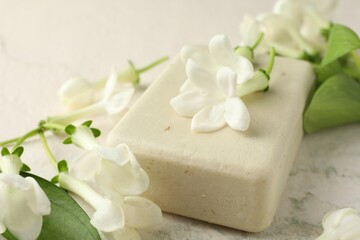 Bar of soap and jasmine flowers on light table, closeup