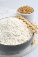 Wheat flour, grain and spikes on white table, closeup