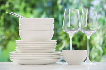 Different clean dishes on white table against blurred green background
