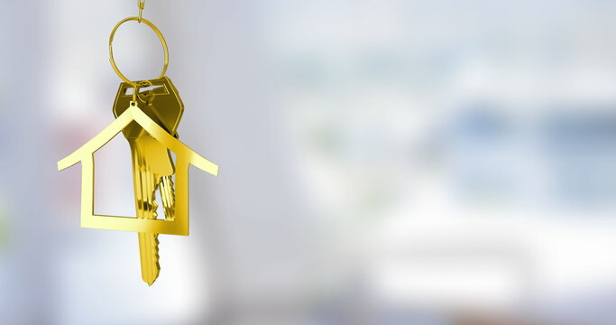 Hanging gold house-shaped keychain dangling metal keys in bright room interior, copy space