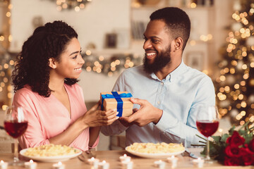 Happy Holidays. Portrait of young black lovers exchanging gifts on anniversary, St Valentine's day...