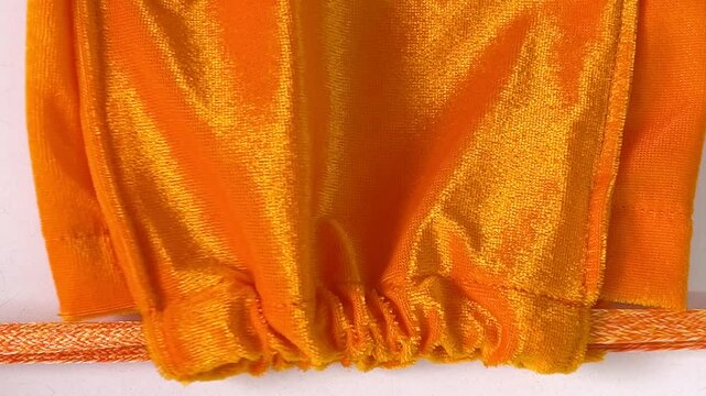 Close-up shot closing yellow velvet drawstring pouch on white tabletop background. Drawstring bag for make merit. Homemade. Bangkok, Thailand./ Slow down video