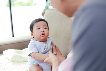 Asian father with little baby sitting on sofa at home. Father and baby bonding helps child development. Family concept. Father's day.