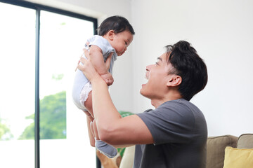 Asian father holding his little baby, he smiles happily. The bond between father and baby, touching, talking, playing, using sounds, helps the baby's development. Family concept. Father's day.