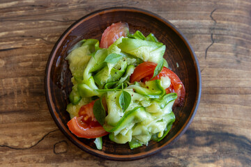Vegetarian salad with fresh marinated zucchini and tomatoes on wooden table, top view