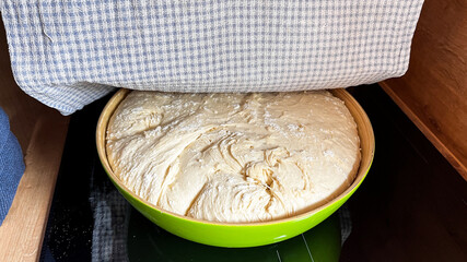 Perfectly done fresh yeast dough in bowl for bread or cake resting under cotton tower. Raw yeast dough resting and rising for baking. Home made process step by step