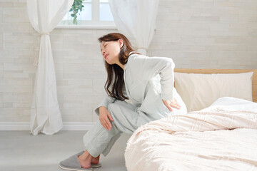 パジャマを着た中年の女性　腰痛