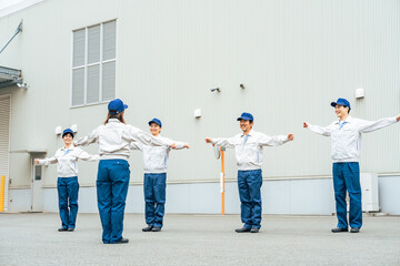 屋外で体操する作業員グループ
