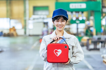 工場でAEDを持つ女性作業員