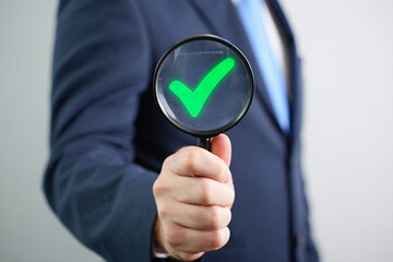 Businessman Holding Magnifying Glass with Green Check Mark