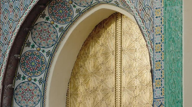 Ornate golden door with intricate geometric patterns, set within a colorful mosaic arch. The craftsmanship and artistry of Moroccan architecture are showcased in this detailed close-up.