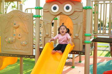 happy toddler baby girl sliding and playing at playground