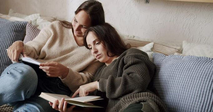 Couple of women read books together and relax at home in the bedroom. lgbt and lesbian women at home. Embrace and holding each other. Romance and portrait of lesbian couple enjoying. LGBT concept