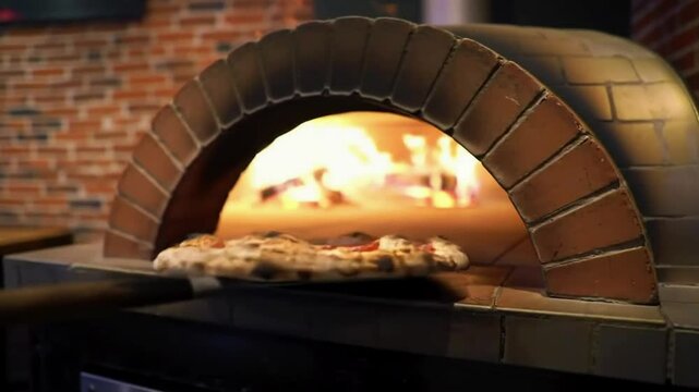 Pizza is baking in a wood fired brick oven with flames