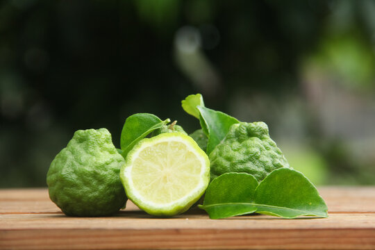 Bergamot fruits or sliced kaffir lime or Citrus hystrix on wooden table and natural green background