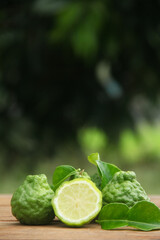 Bergamot fruits or sliced kaffir lime or Citrus hystrix on wooden table and natural green background