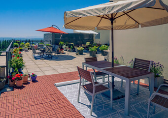 Large rooftop patio garden with umbrellas and patio furniture far above Fraser Valley, BC, Canada.