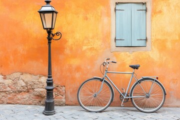 Vintage bicycle leaning against a vibrant orange wall with a light post.