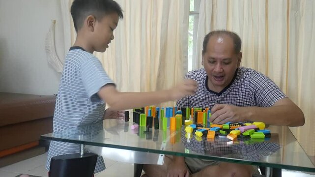 Father and son playing domino in the living room with happy 