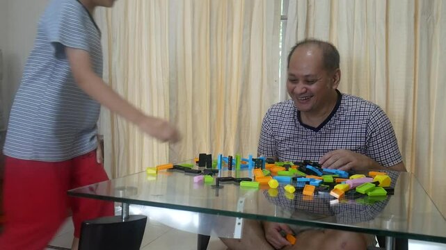 Father and son playing domino in the living room with happy 