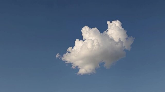 A single fluffy cloud floats against a clear blue sky, captured from a low-angle perspective, resembling a serene video still. Live desktop wallpaper.
