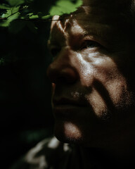 ethereal portrait of redheaded man in dappled forest light, freckled skin glowing golden, emerald eyes catching sunbeams through leaves.