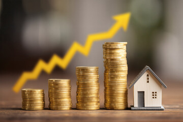 Home Investment Growth: Stacks of coins and a small house showcase the potential appreciation of real estate.