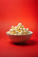 Close up of popped pop corn in bowl red background copy space