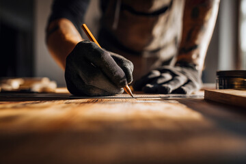 Focused craftsman meticulously marking wood with pencil and ruler, showcasing precision and dedication to woodworking.