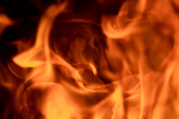 Close-up image of bright orange flames against a backdrop of black ash and burnt debris. A strong visual composition depicting the power, energy, and beauty of nature in the form of the fire element. 