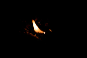 Close-up image of bright orange flames against a backdrop of black ash and burnt debris. A strong visual composition depicting the power, energy, and beauty of nature in the form of the fire element. 