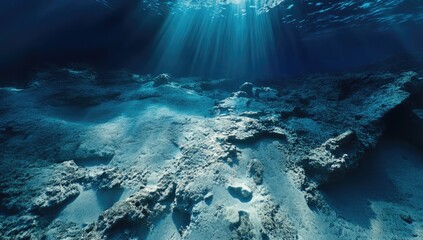 Underwater scene, sunbeams pierce dark blue water, illuminating light beige seabed with coral
