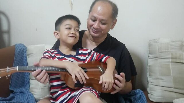 Happy father playing ukulele with son 