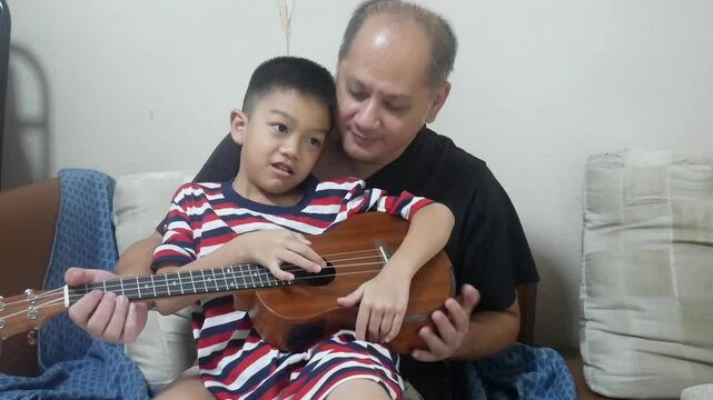 Happy father playing ukulele with son 