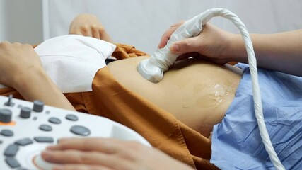 Close-up of the hands of an ultrasound doctor performing an ultrasound of the abdominal cavity on a patient with a modern scanner. Modern medical diagnostic equipment in a reproductive clinic.