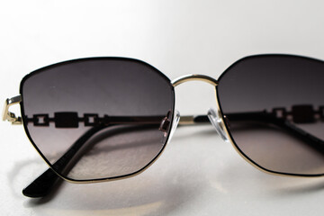 Close-up of stylish sunglasses with dark lenses and metal frame on a white background