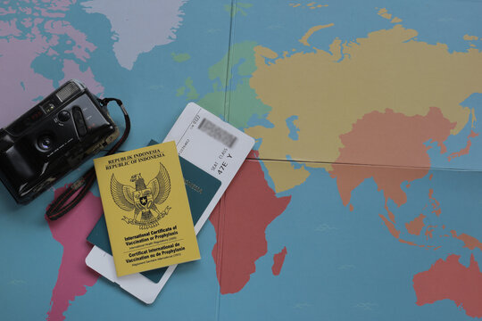 Top view of travel concept, with man hand pointing on map, passport, vaccine certificate, phone, roll film camera, and boarding pass