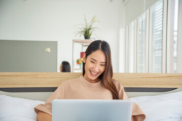 Happy asian woman video call web conference sitting on cozy sofa in living room at home. Smile Female asian people use laptop notebook computer headphones online call working from home watching video
