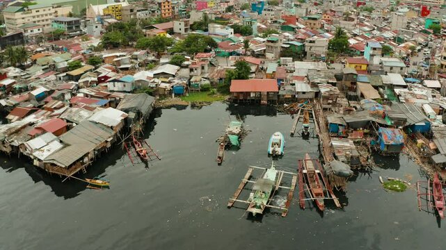 Slums in Manila on the bank of a river polluted with garbage, aerial view.