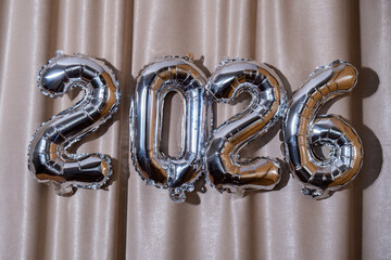 Happy new year 2026 metallic balloons on atlas textile background. Greeting card silver foil...