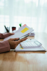 A close-up shows hands reviewing financial charts and documents on a clipboard, suggesting detailed...